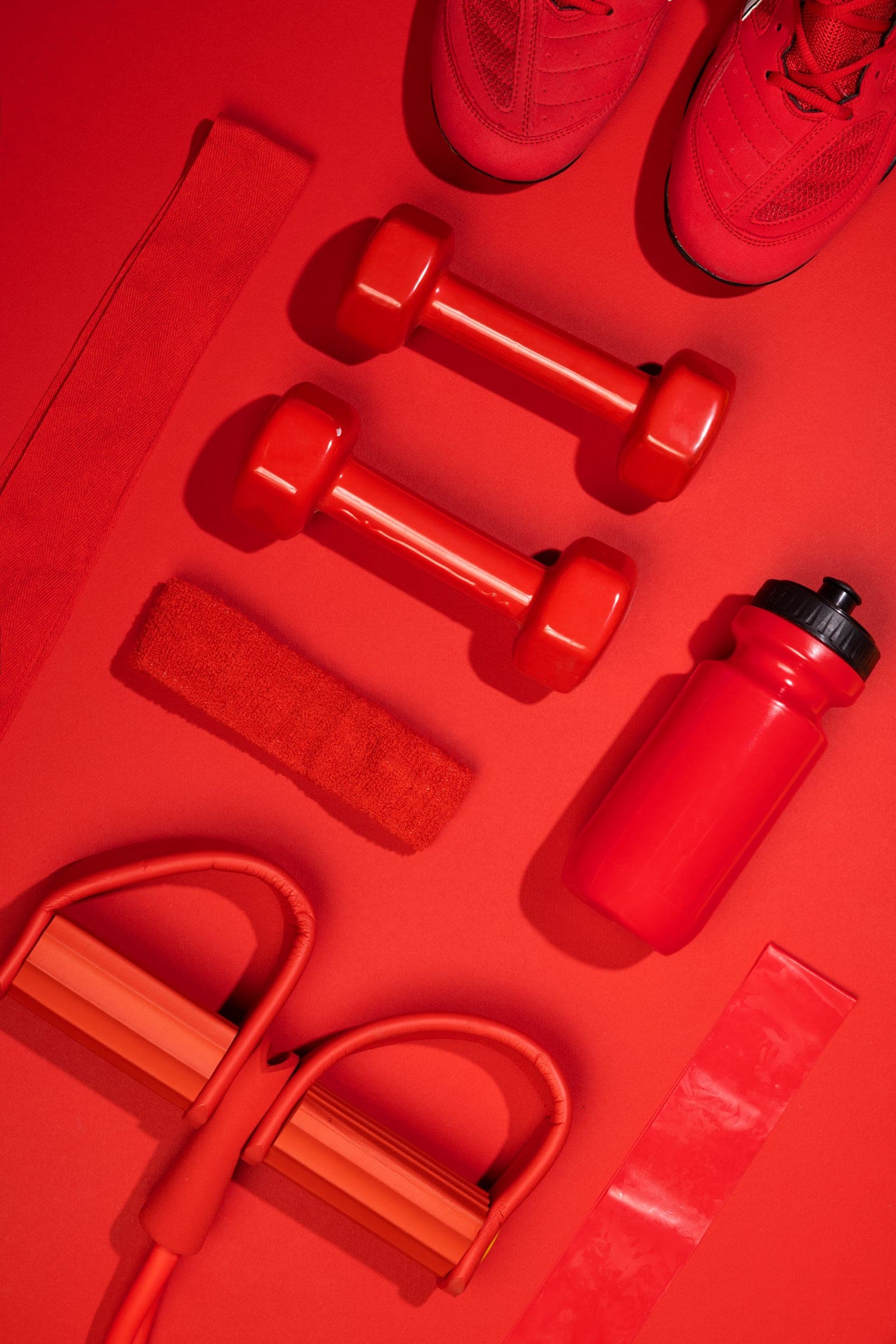 Gantere și accesorii de fitness roșii, aranjate geometric